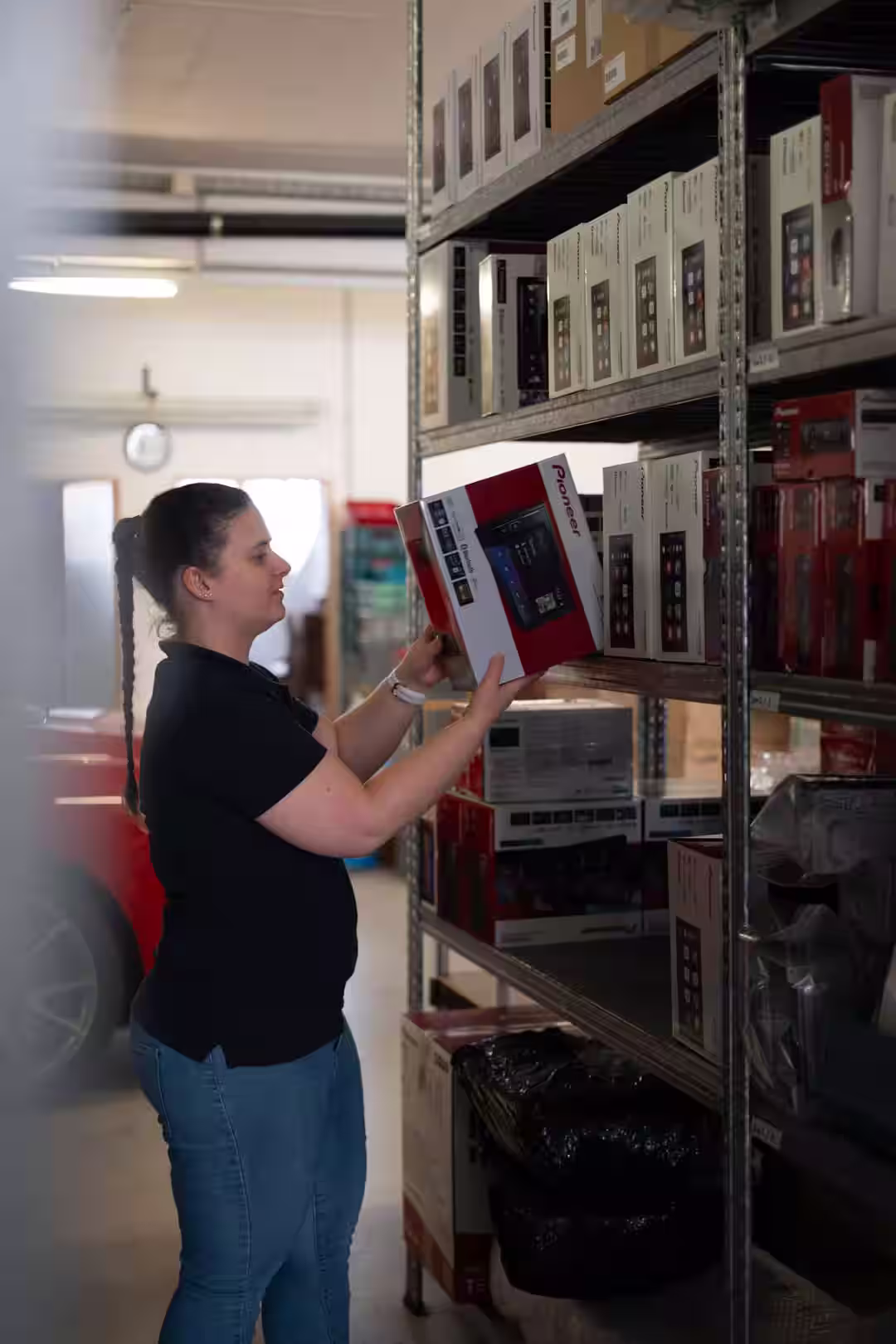 Logistik Mitarbeiterin von Exclusiv Car-HiFi holt Lautsprecher aus Regal