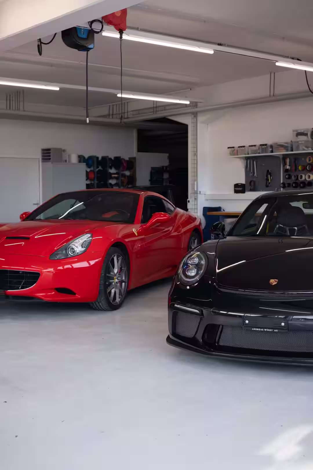Ein roter Ferrari und schwarzer Porsche in der Werkstatt von Exclusiv Car-HiFi